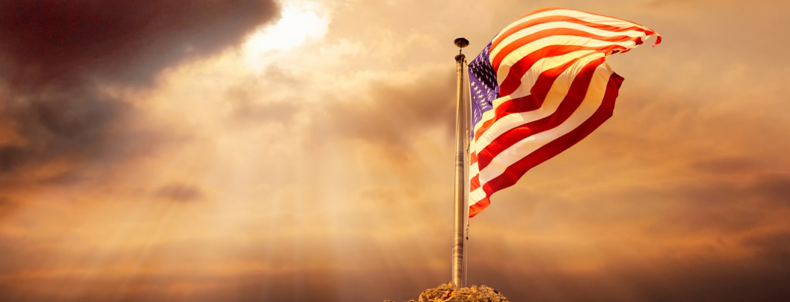 US flag waving in sun rays